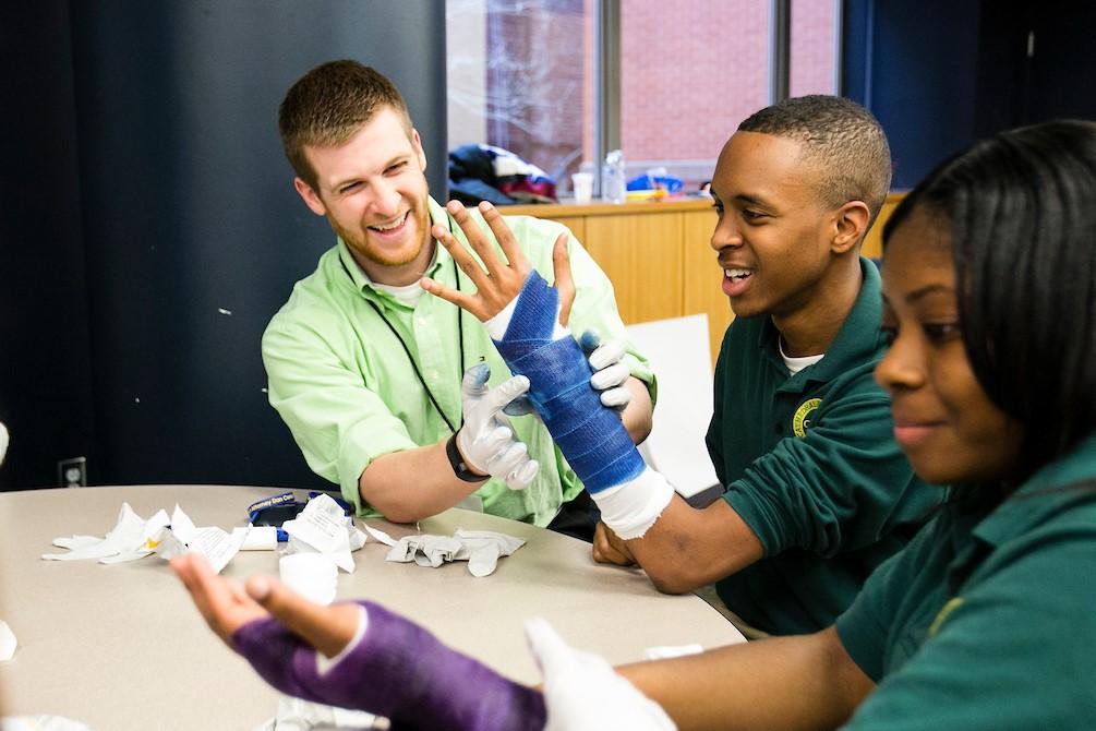 Brian Schmidtberg, M16, puts a cast on Cathedral High School junior’s arm during a field trip to the School of Medicine