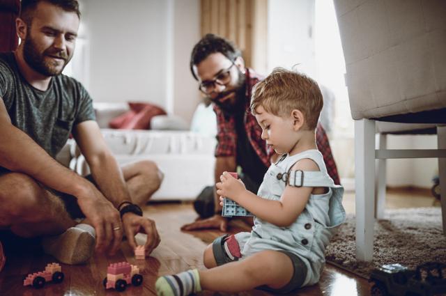 Two dads playing with toddler.