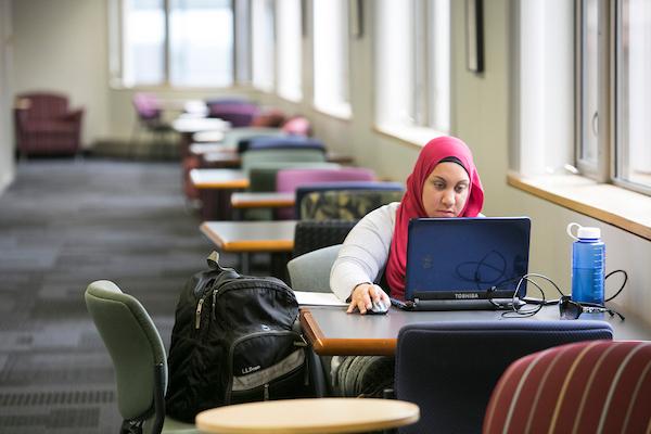 Student studying while sitting on desk with laptop