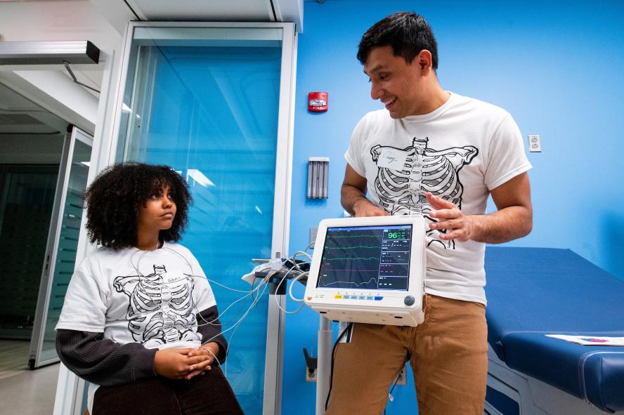 Wright Academy student listened to a Tufts University School of Medicine student volunteer talk about measuring the heart's activity through an EKG or electrocardiogram, which they then saw in practice.