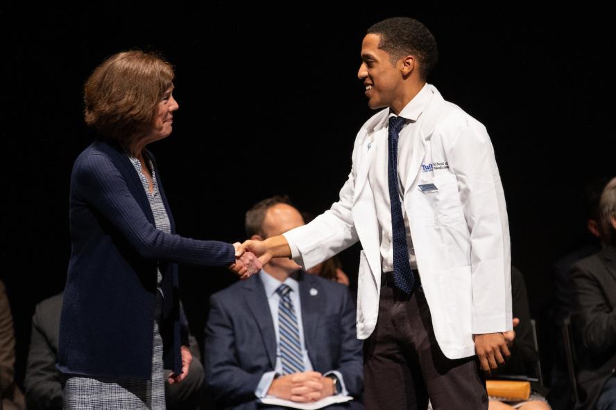 Dean Helen Boucher shaking hands with a student at a White Coat Ceremony