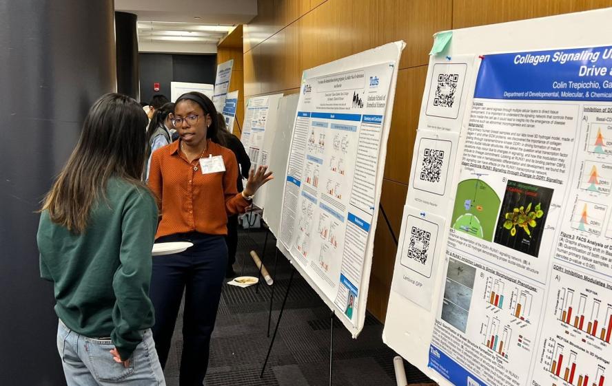 Two students at the 2023 Charlton Poster Competition in MED 114, discussing a research poster
