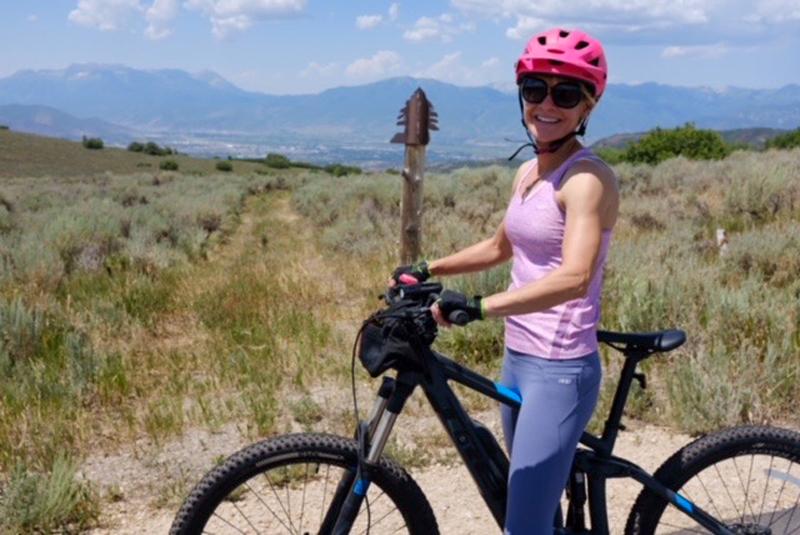 Beth pictured during a hike in Utah; poses with her bike.