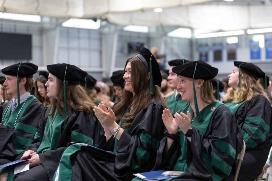 Members of the MD class of 2026 at Commencement clapping and smiling.