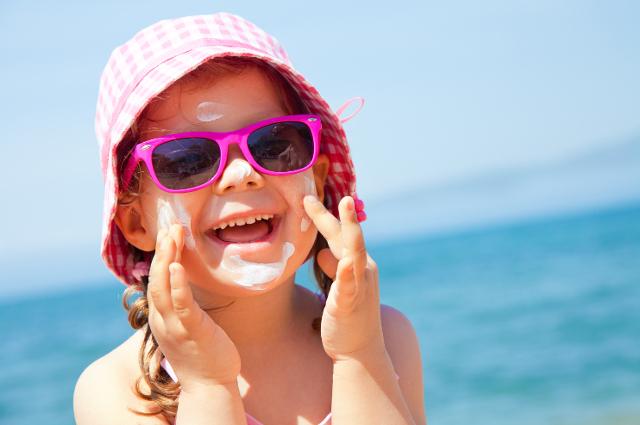 A child applying sunscreen on the beach