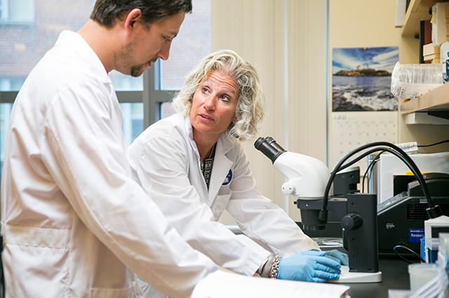 Caroline Genco, vice provost for research, talks with a postdoc in her lab