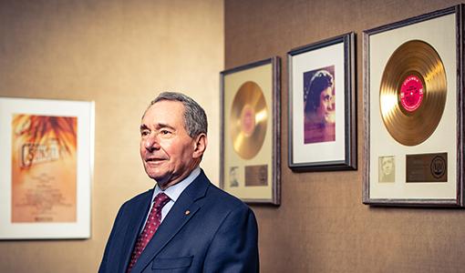 Otolaryngologist Robert Ossoff, D73, M75, standing in front of 2 gold records