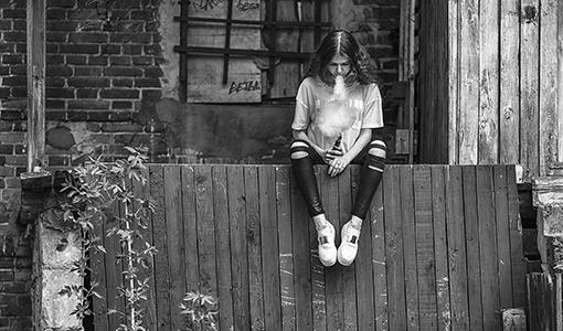 Teenage girl sitting on a fence while vaping