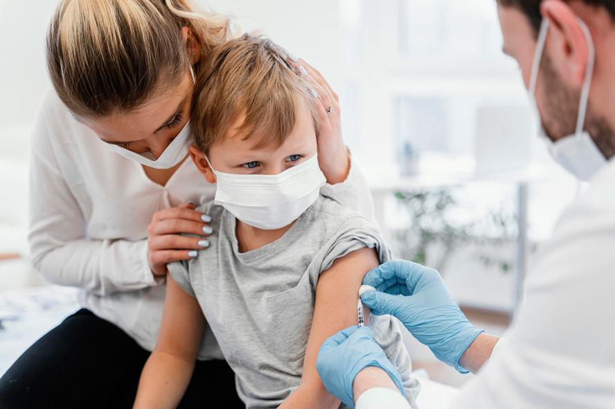 A child prepares to receive an injection from a medical professional. A Tufts pediatrics expert explains how vaccine dosages for children are developed and why it’s important for young people to be vaccinated