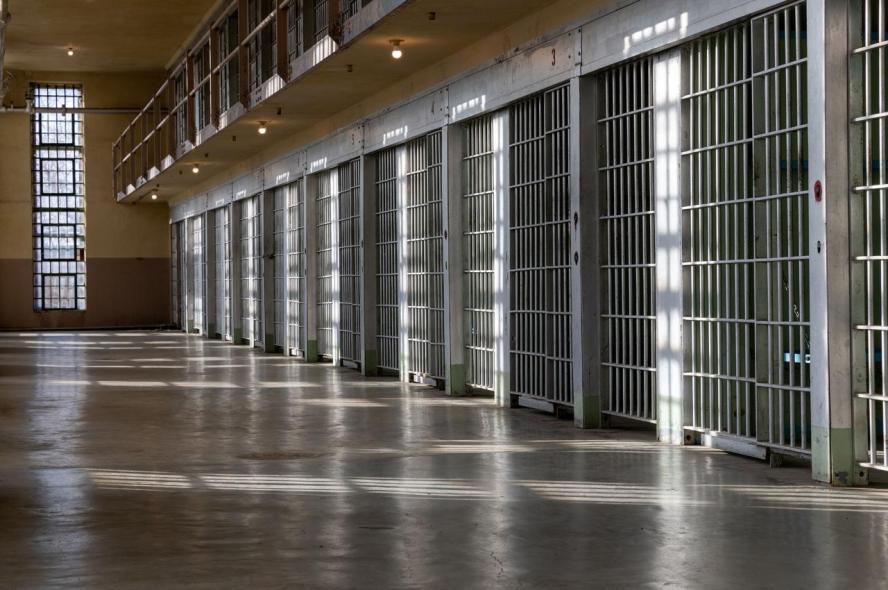 A hallway lined with jail cells and silver bars 
