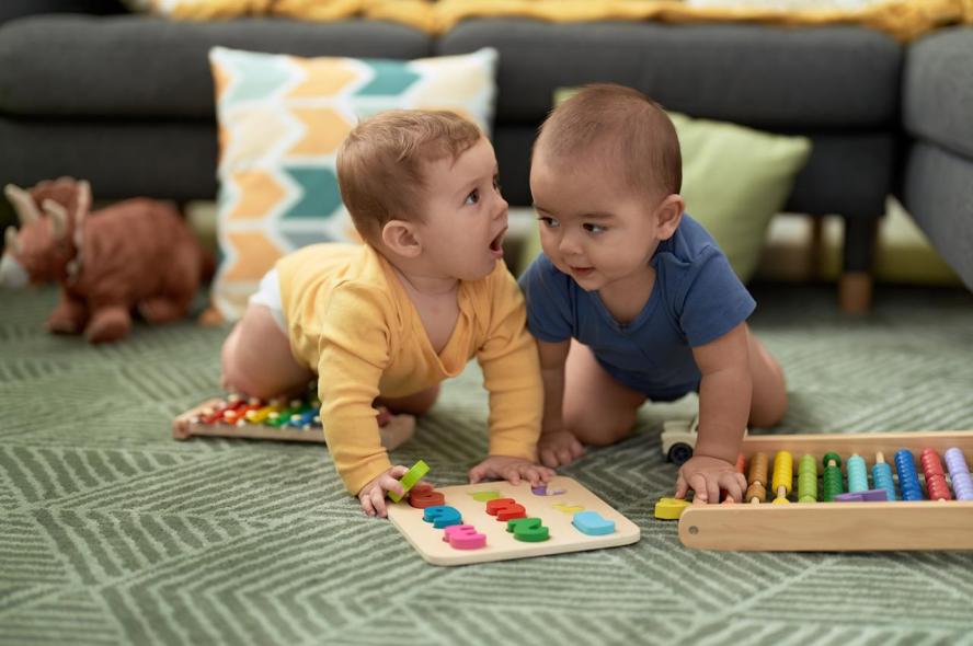 two infants play with math toys on the floor