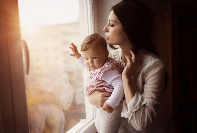 Mother with her baby daughter by the window