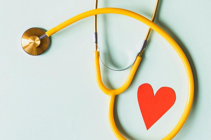 A yellow stethoscope next to a red paper heart