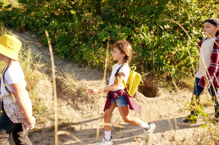 Three kids wearing sneakers on a hike on a dirt path