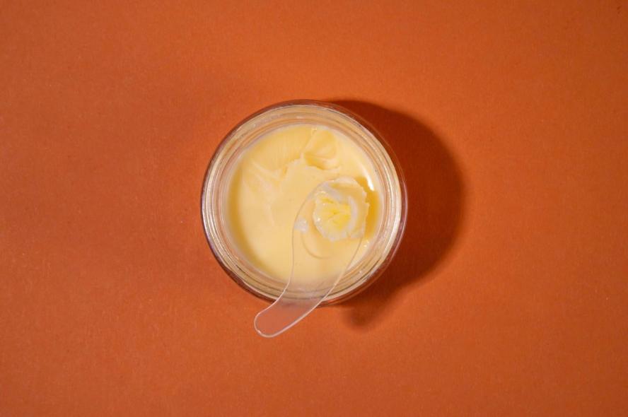 A glass jar filled with beef tallow on an orange background