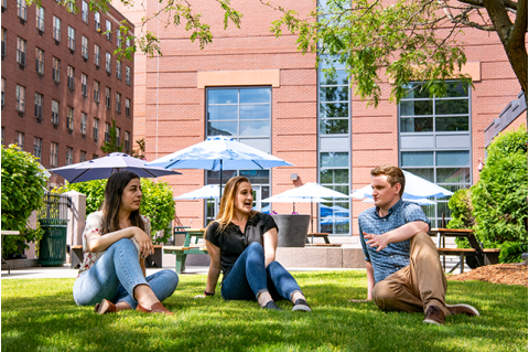 Three students sitting on the grass in the Jaharis Courtyard