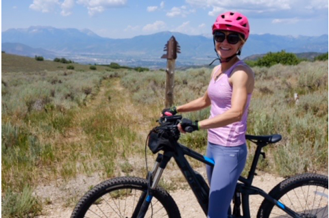 Beth pictured during a hike in Utah; poses with her bike.