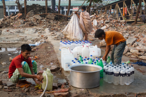 Boys filling water containers amid squalor in Dhaka, Bangladesh
