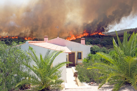 House with raging wildfire in background