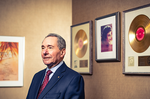 Otolaryngologist Robert Ossoff, D73, M75, standing in front of 2 gold records
