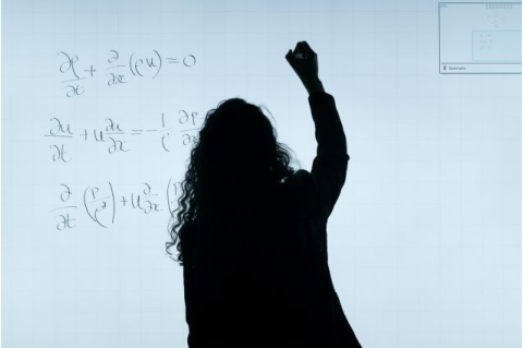 Shadow of woman writing equation on whiteboard