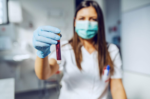 A lab technician holds a test tube containing a blood sample.