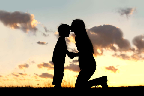 Silhouetted against a sunset, a woman kisses the forehead of a child. Pediatric researcher Robert Sege explains why child abuse actually decreased during the COVID, despite predictions it would rise.