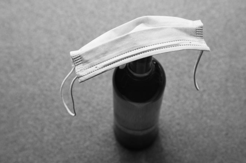 A wine bottle covered in a face mask in black-and-white
