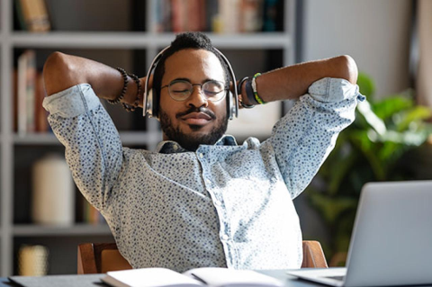 Relaxed african business man wear wireless headphones enjoy listen music with eyes closed