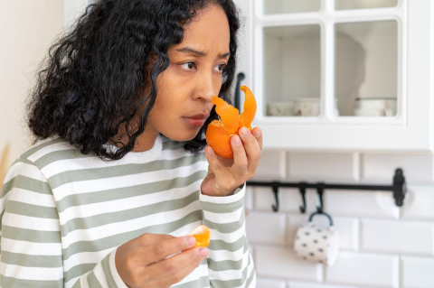 A young woman sniffs an orange to test her sense of smell 
