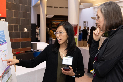 Two Tufts community members standing beside a poster with scientific findings