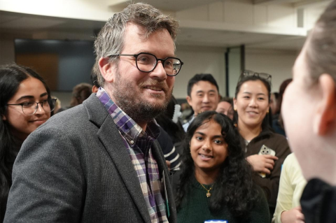 a smiling man standing in a crowd of students
