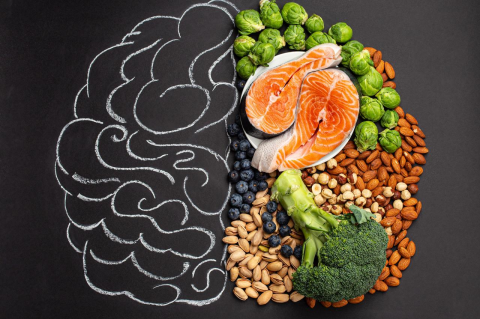 Chalk-drawn brain with assorted foods for brain health, such as broccoli, fish, and nuts