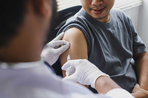 A patient receives a flu vaccine from a medical professional.