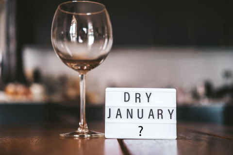 An empty wine glass next to a small sign that says &quot;Dry January?&quot;