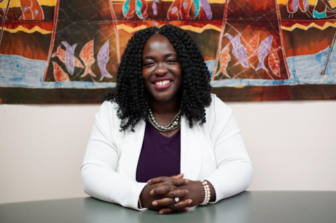 Ndidiamaka Amutah-Onukagha sits at a desk and smiles