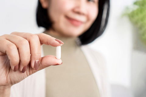 A woman holds a probiotic supplement between her fingers