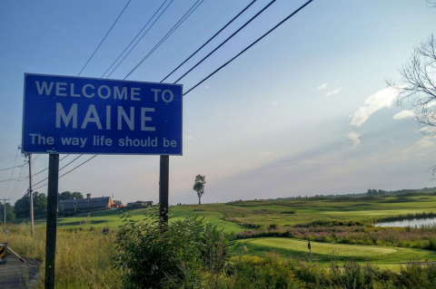 A &quot;Welcome to Maine&quot; sign along a rural road.