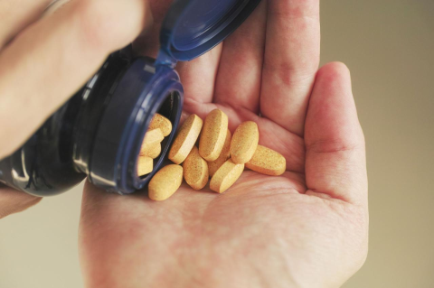 Yellow tablets are poured out of a bottle of B complex vitamins