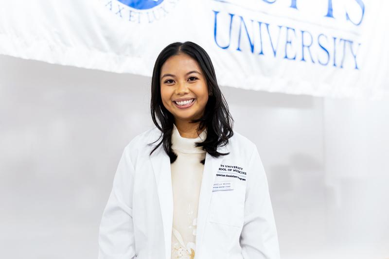 Student poses wearing white coat